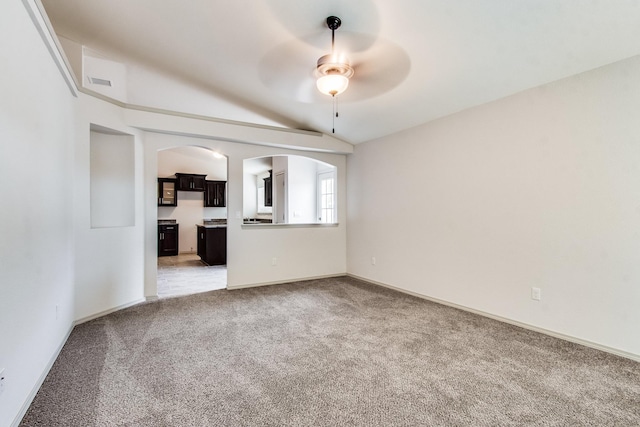 unfurnished living room featuring ceiling fan, arched walkways, lofted ceiling, light carpet, and baseboards