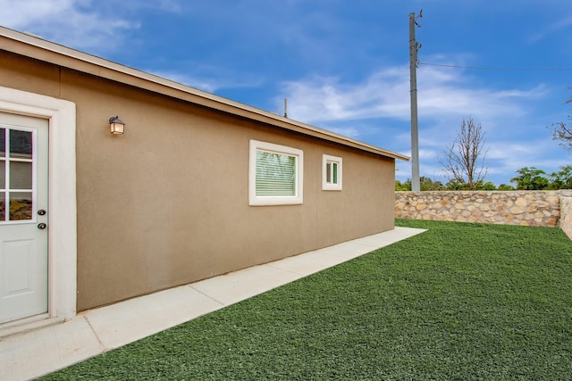 view of side of home featuring a lawn and stucco siding