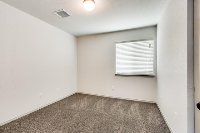 empty room with carpet flooring, visible vents, and baseboards