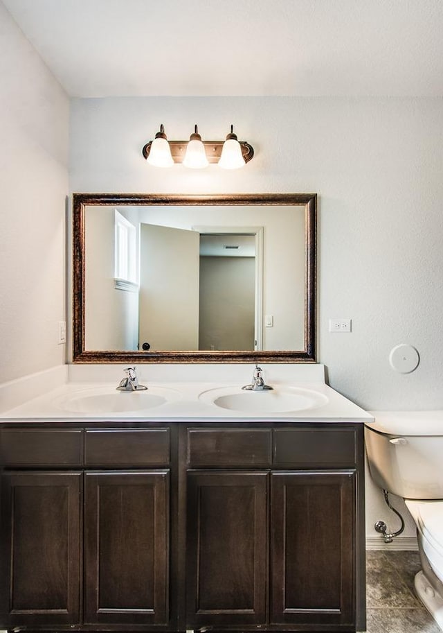 bathroom featuring toilet, double vanity, and a sink