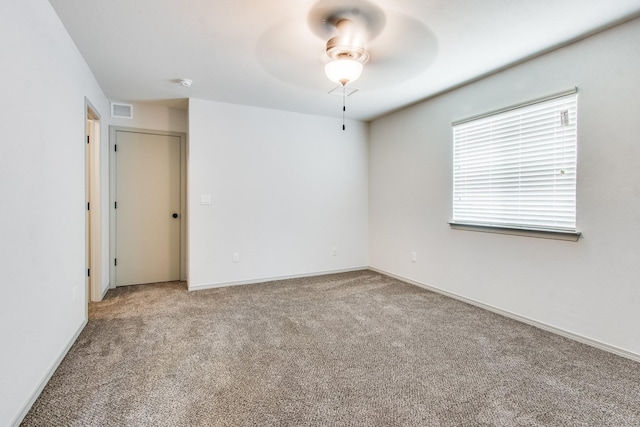 carpeted empty room featuring baseboards, visible vents, and a ceiling fan