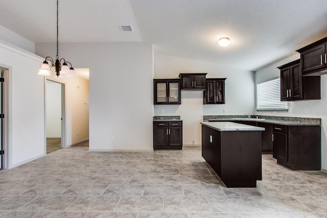 kitchen with a notable chandelier, lofted ceiling, visible vents, a kitchen island, and dark brown cabinetry