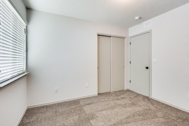 unfurnished bedroom with carpet, visible vents, and a closet