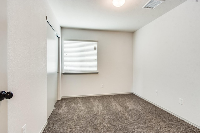 unfurnished room with baseboards, visible vents, and dark carpet