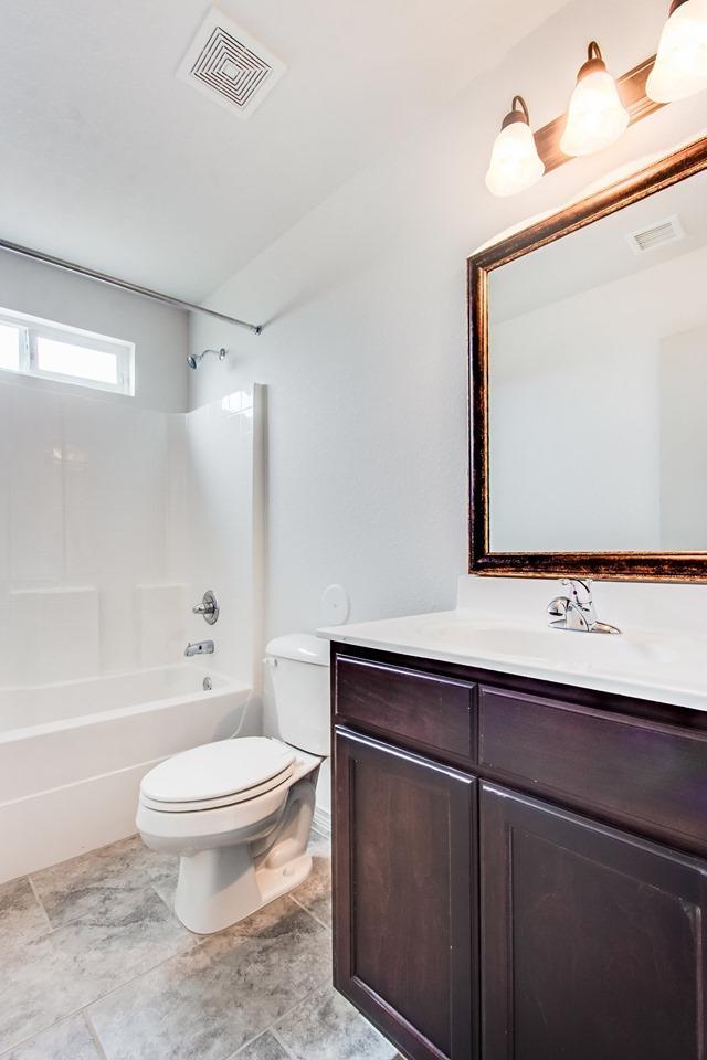 full bath with toilet, bathtub / shower combination, visible vents, and vanity