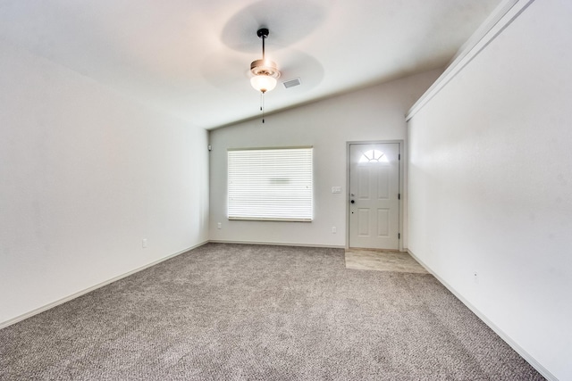 carpeted empty room with lofted ceiling, baseboards, visible vents, and a ceiling fan