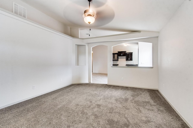 carpeted spare room featuring arched walkways, baseboards, visible vents, and a ceiling fan