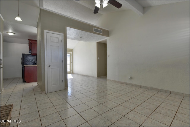 empty room with light tile patterned floors, visible vents, lofted ceiling with beams, ceiling fan, and a textured ceiling