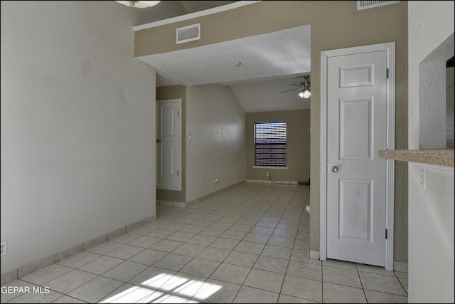 spare room with light tile patterned floors, visible vents, baseboards, ceiling fan, and vaulted ceiling