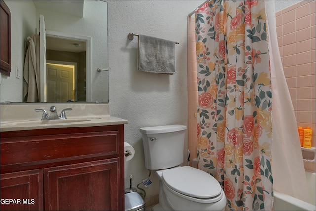 bathroom with toilet, vanity, shower / tub combo with curtain, and a textured wall