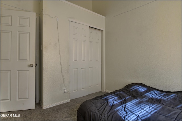 carpeted bedroom featuring baseboards, a closet, and a textured wall