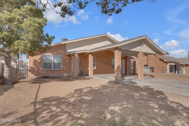 view of front facade featuring concrete driveway, brick siding, and fence