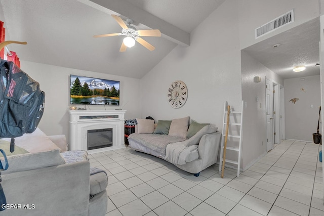 living area with vaulted ceiling with beams, visible vents, a ceiling fan, a glass covered fireplace, and light tile patterned flooring