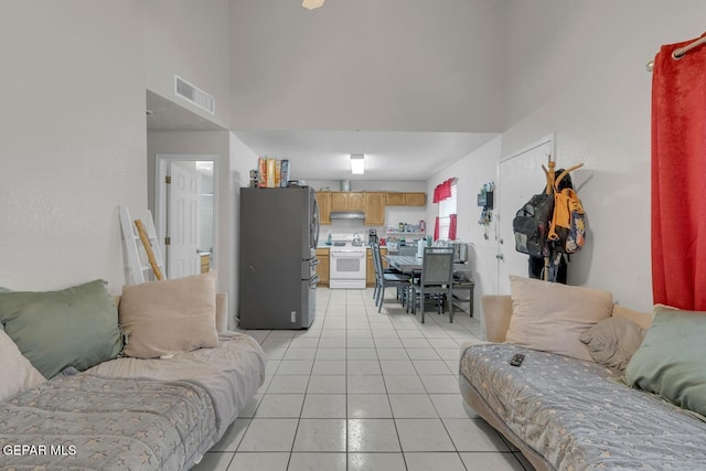 living room featuring visible vents, a towering ceiling, and light tile patterned floors