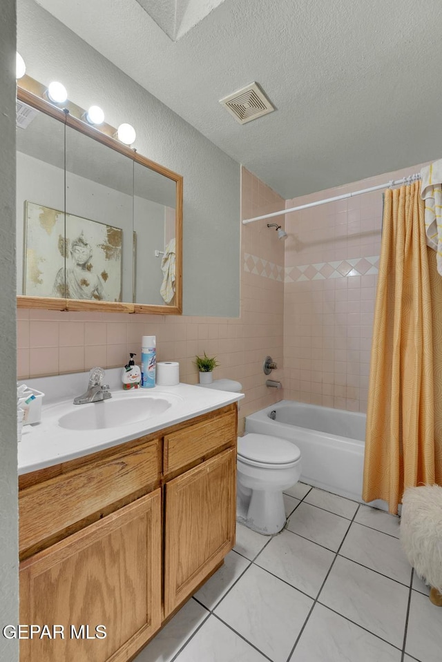 full bath featuring tile walls, visible vents, shower / bath combo with shower curtain, a textured ceiling, and vanity