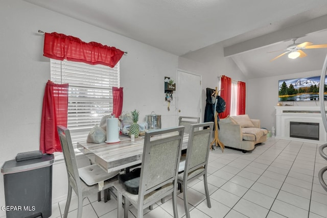 tiled dining room featuring vaulted ceiling, ceiling fan, and a glass covered fireplace