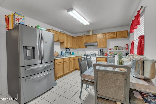 kitchen with white gas range, light countertops, light brown cabinets, under cabinet range hood, and stainless steel fridge with ice dispenser