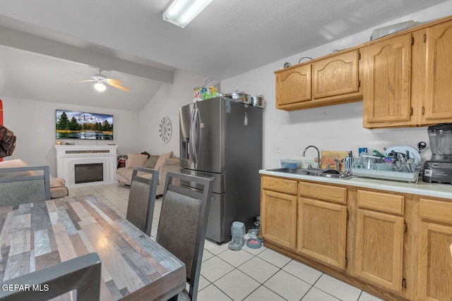 kitchen featuring a glass covered fireplace, stainless steel fridge with ice dispenser, open floor plan, light countertops, and a sink