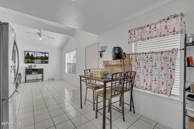 dining room with vaulted ceiling, a textured ceiling, light tile patterned flooring, and a ceiling fan