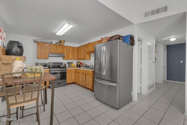 kitchen with light tile patterned floors, visible vents, appliances with stainless steel finishes, light countertops, and under cabinet range hood