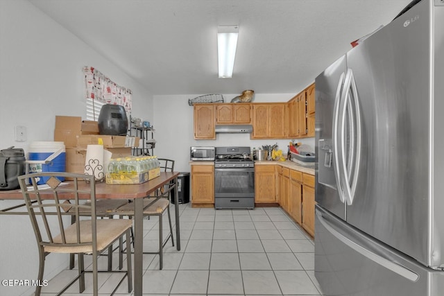 kitchen featuring stainless steel appliances, light countertops, under cabinet range hood, and light tile patterned floors