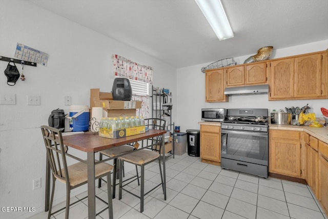 kitchen featuring under cabinet range hood, appliances with stainless steel finishes, light countertops, and light tile patterned flooring