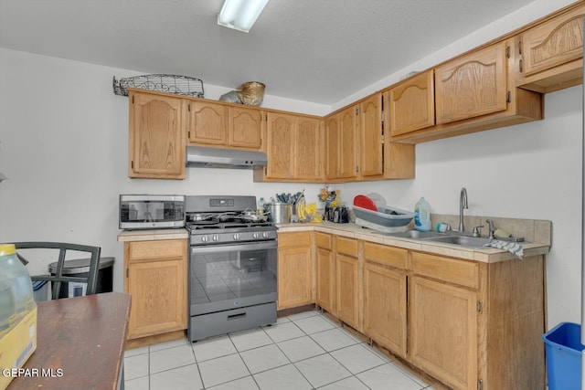 kitchen with tile countertops, light tile patterned floors, under cabinet range hood, a sink, and appliances with stainless steel finishes