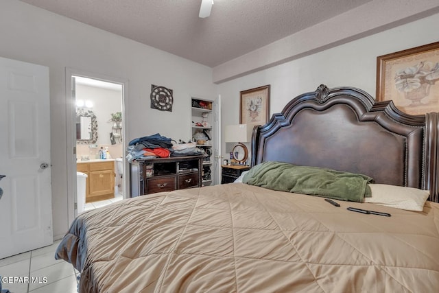 bedroom featuring light tile patterned floors, ceiling fan, a textured ceiling, and ensuite bathroom