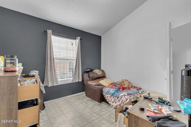 bedroom with a textured ceiling, light floors, and vaulted ceiling