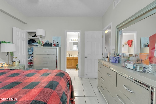 bedroom with a walk in closet, light tile patterned floors, a closet, visible vents, and a textured ceiling