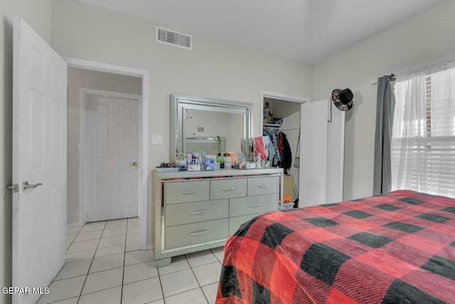 bedroom with a spacious closet, visible vents, and light tile patterned flooring