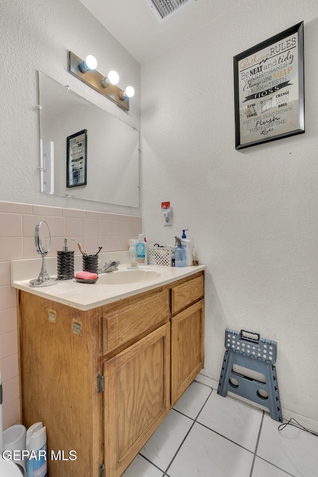 bathroom with visible vents, tile patterned floors, vanity, and tile walls