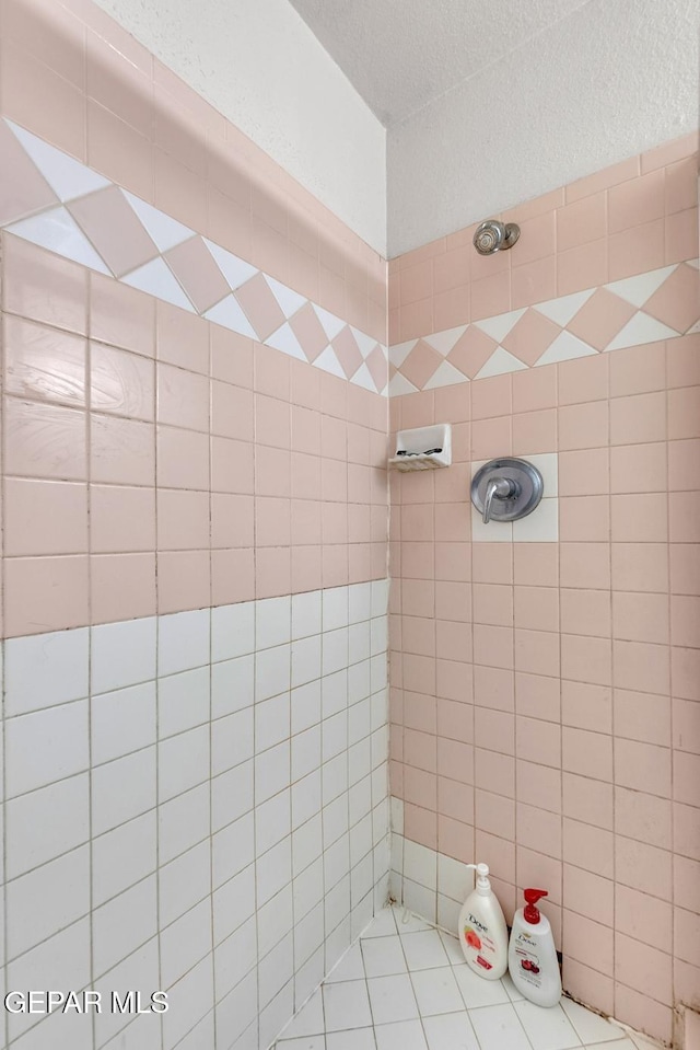 full bathroom with a tile shower and a textured ceiling