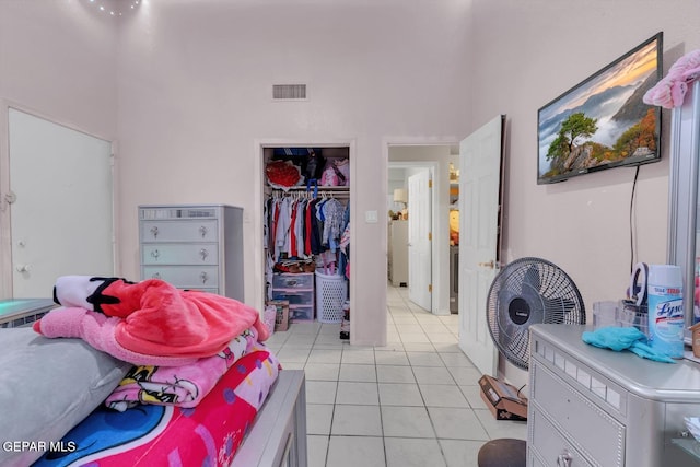 bedroom featuring a closet, visible vents, a high ceiling, and light tile patterned flooring