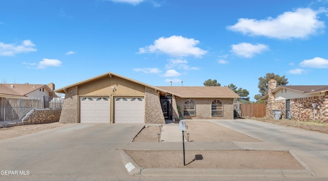 single story home featuring concrete driveway, brick siding, an attached garage, and fence