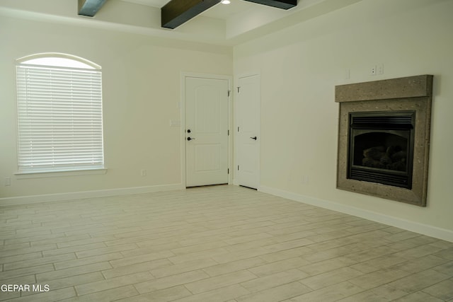 unfurnished living room featuring light wood finished floors, a fireplace, baseboards, and beamed ceiling