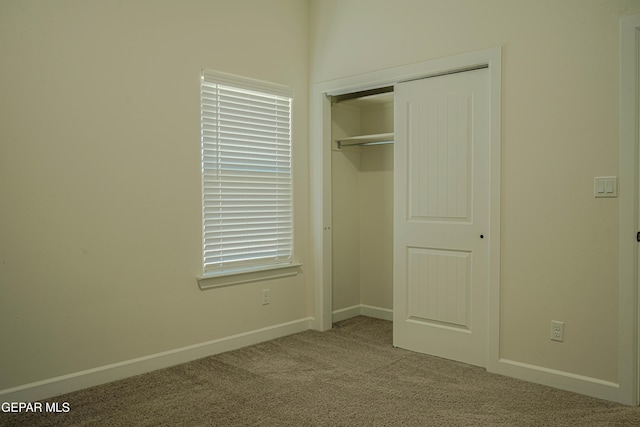 unfurnished bedroom with carpet, a closet, and baseboards