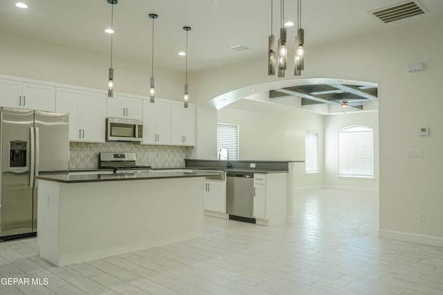 kitchen with stainless steel appliances, dark countertops, visible vents, hanging light fixtures, and white cabinets