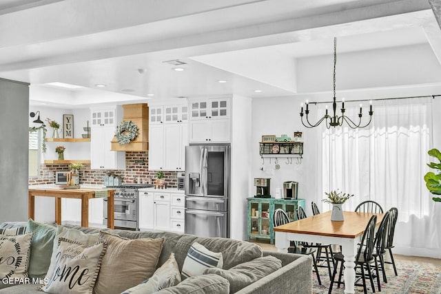 kitchen featuring white cabinets, glass insert cabinets, appliances with stainless steel finishes, open floor plan, and backsplash