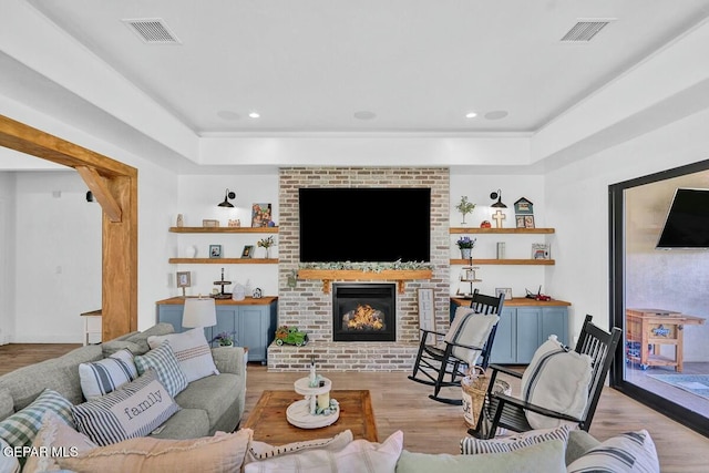 living area featuring light wood-type flooring, a fireplace, visible vents, and recessed lighting