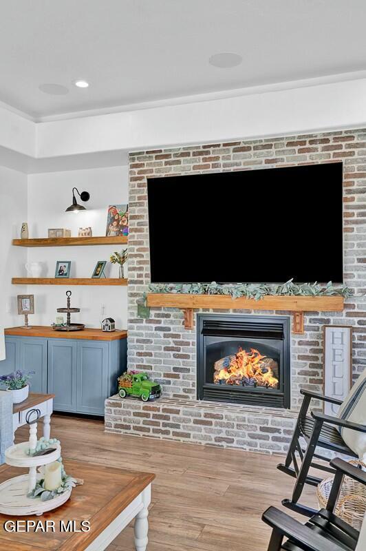 interior space with a brick fireplace, wood finished floors, and recessed lighting