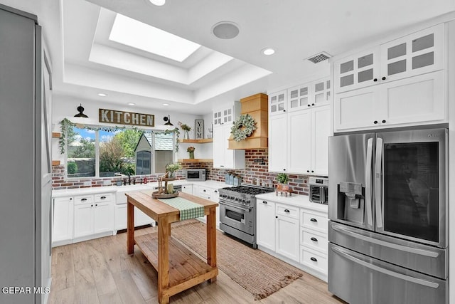 kitchen with stainless steel appliances, a skylight, visible vents, decorative backsplash, and a raised ceiling