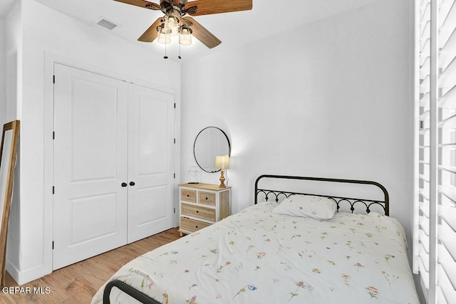 bedroom featuring visible vents, a closet, wood finished floors, and a ceiling fan