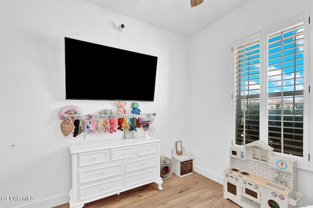 interior space with baseboards, a ceiling fan, and light wood-style floors