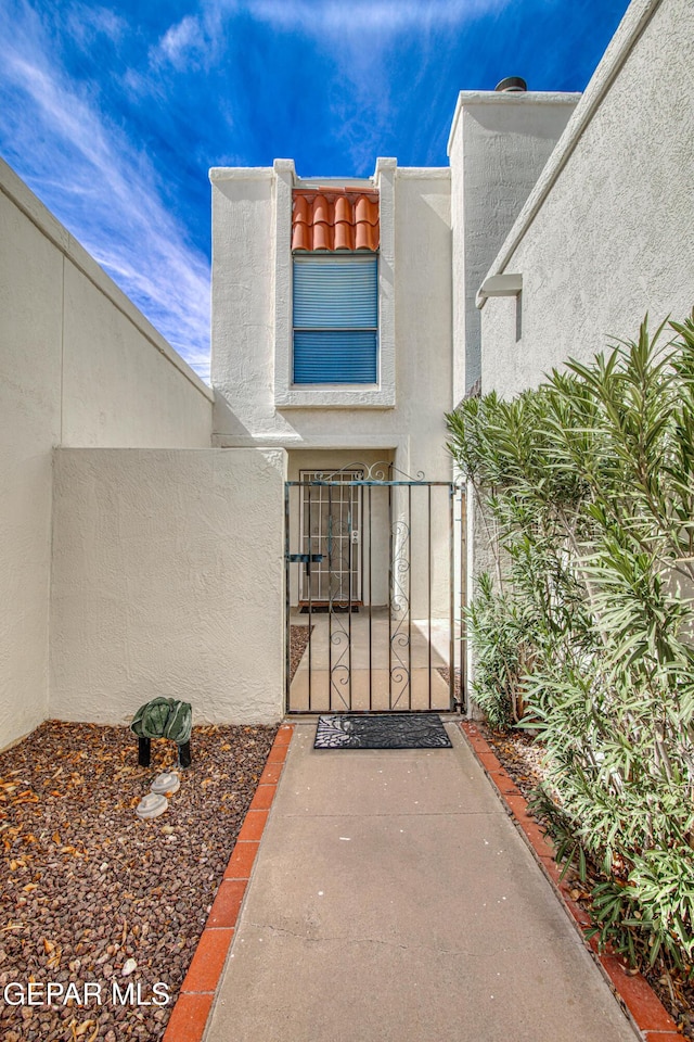 entrance to property with a gate and stucco siding