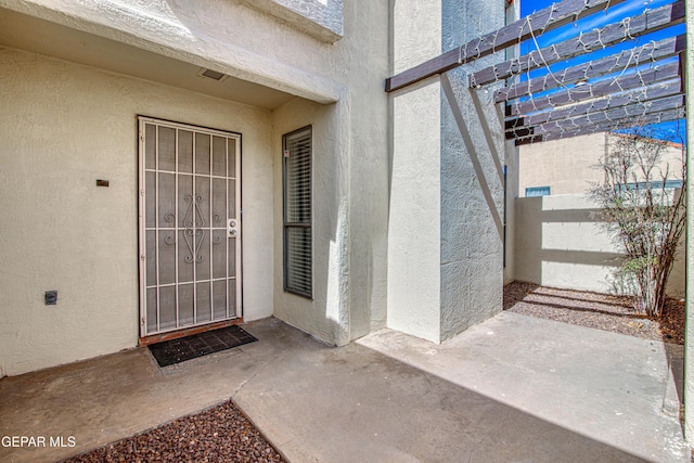 view of exterior entry with a patio area and stucco siding