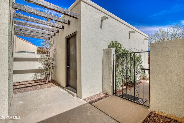 exterior space with fence, a gate, and stucco siding