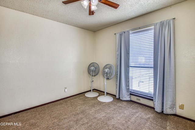 carpeted spare room featuring a textured ceiling, a textured wall, a ceiling fan, and baseboards