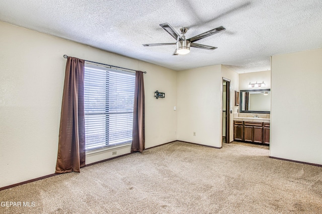 unfurnished room with a ceiling fan, light carpet, a textured ceiling, and baseboards