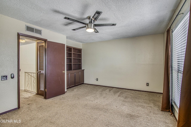 unfurnished bedroom with visible vents, a textured wall, light carpet, and a textured ceiling